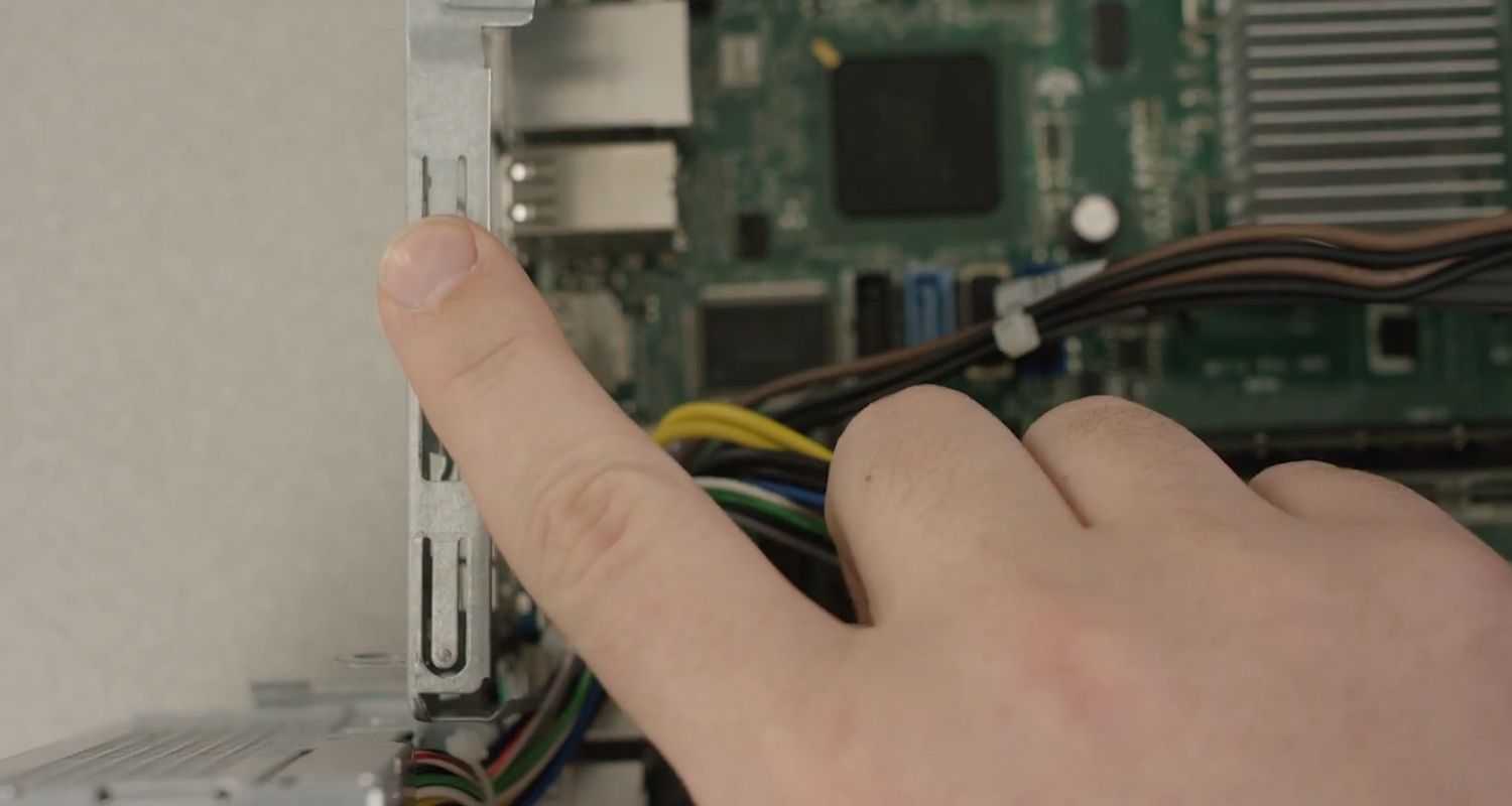 Un dedo tocando una de las superficies metálicas sin pintar del interior de un PC de sobremesa para descargar la electricidad estática